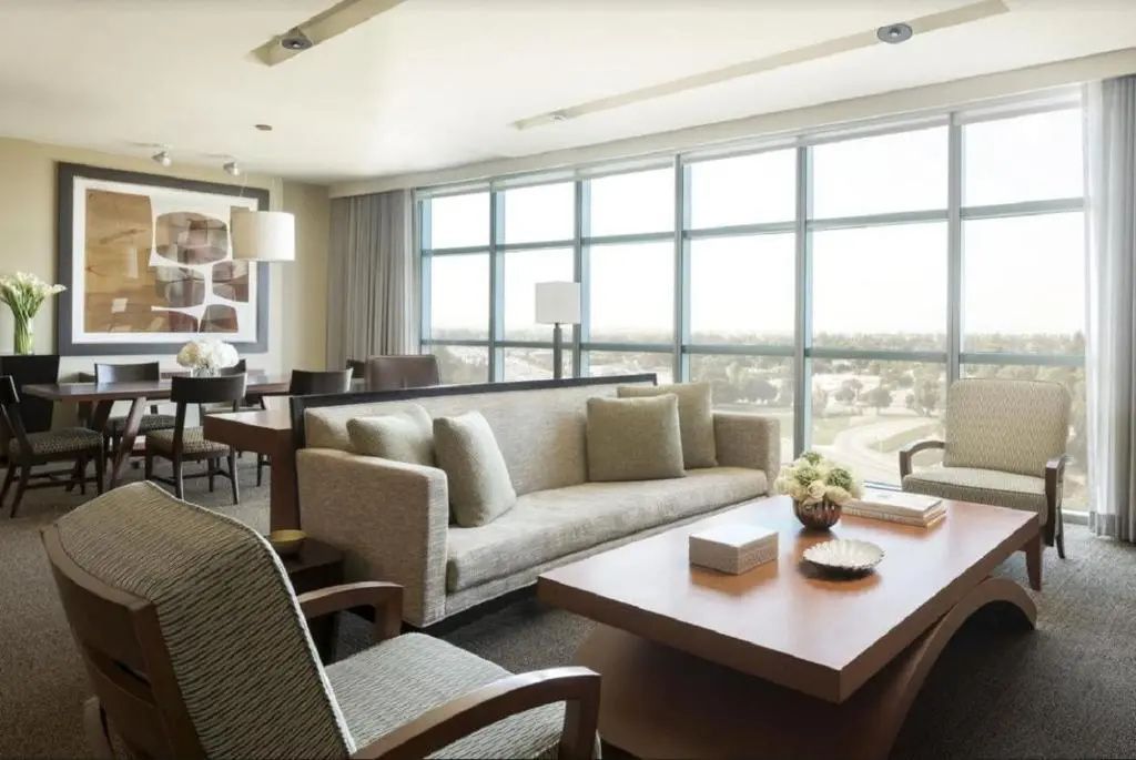 Geräumiges Wohnzimmer einer Suite mit hellem Sofa und großer Fensterfront.