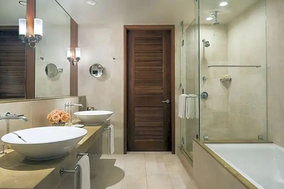 Badezimmer mit doppeltem Waschtisch, großer Spiegelfläche und gläserner Dusche.