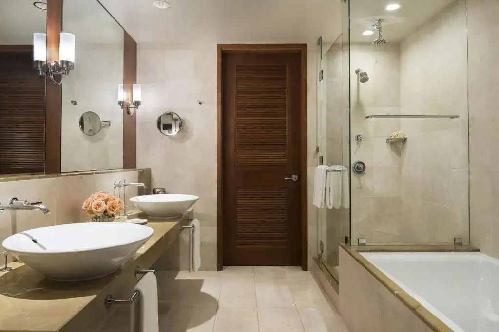 Badezimmer mit zwei Aufsatzwaschbecken, Glasdusche und Badewanne.