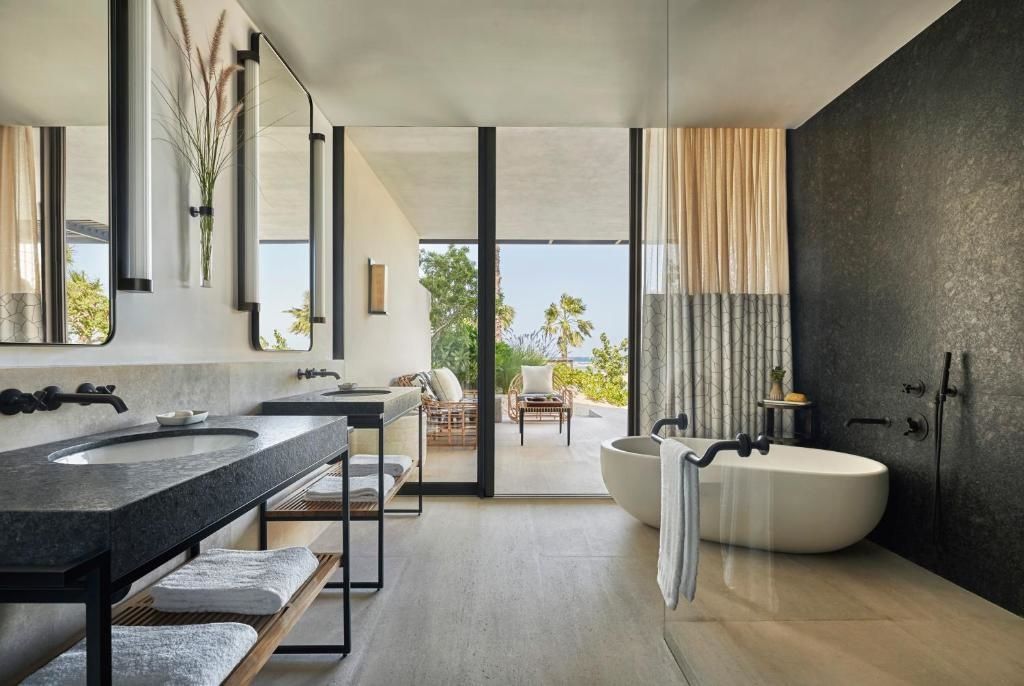 Modernes Badezimmer mit Waschtisch, freistehender Badewanne und Zugang zur Terrasse