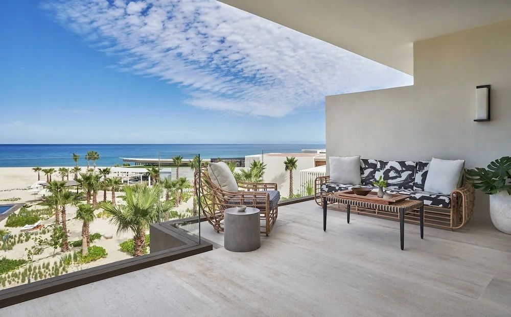Terrasse mit modernen Sitzmöbeln, Glasgeländer und Blick auf Palmen und das Meer