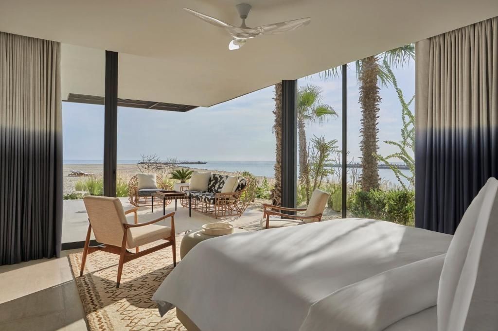 Blick vom Schlafzimmer über die Terrasse auf das Meer und Palmen.