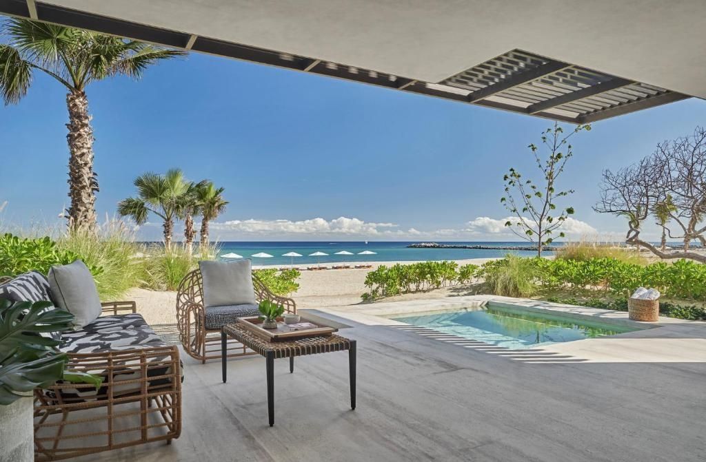 Überdachte Terrasse mit Sitzmöbeln, kleinem Pool und freiem Blick auf Strand und Meer