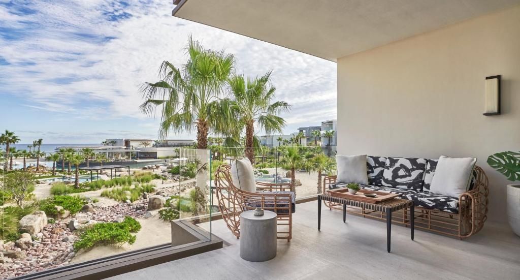 Möblierter Balkon mit Sitzgelegenheiten und Blick auf Palmen und die Gartenanlage.