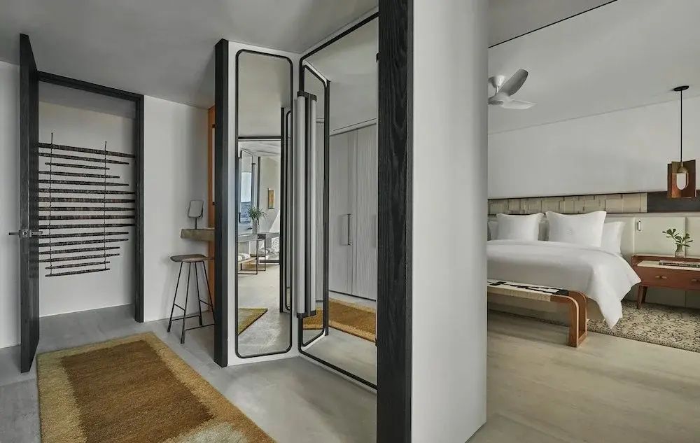 Ankleidebereich mit bodentiefem Spiegel und Blick in das angrenzende Schlafzimmer.
