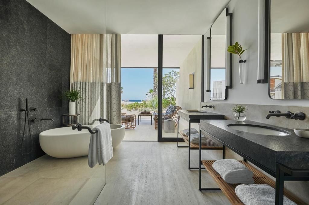 Badezimmer mit freistehender Badewanne, Doppelwaschtisch und Blick auf die Terrasse