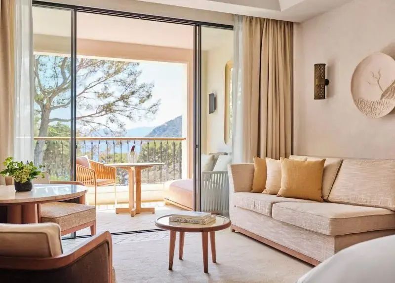 Wohnbereich im Zimmer mit hellen Polstermöbeln und Blick zum Balkon.