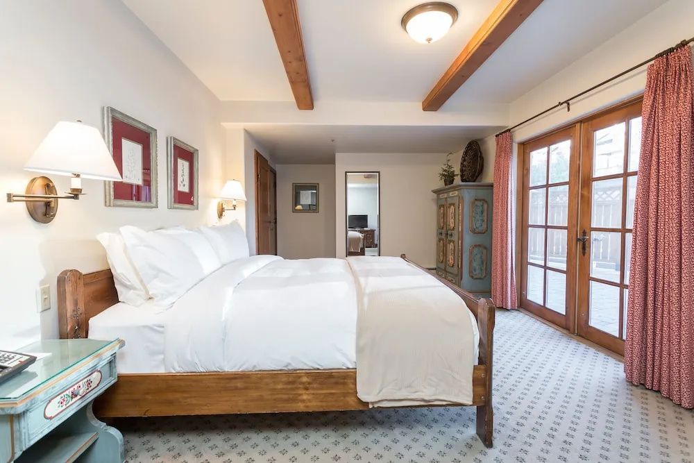 Großes Bett mit weißer Bettwäsche, Holzdecke und Glastür zum Außenbereich im Schlafzimmer.