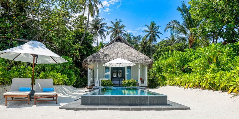 Exklusive Strandvilla mit Pool und Liegestühlen umgeben von tropischer Vegetation