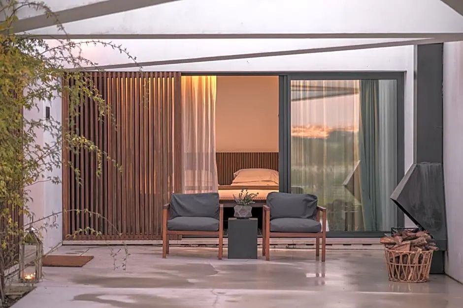 Terrassensitzbereich mit zwei Sesseln und Blick in das beleuchtete Schlafzimmer.