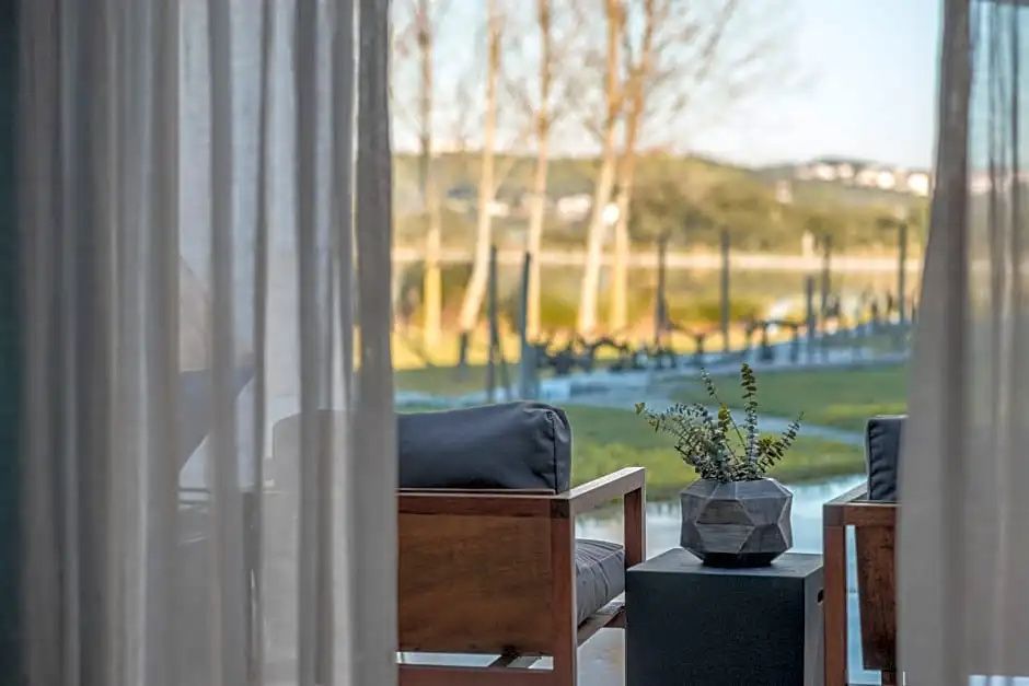 Blick durch transparente Vorhänge auf Bäume und Landschaft von der Terrasse aus.