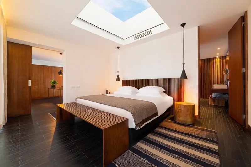 Schlafzimmer mit großem Doppelbett, Dachfenster, Holzfußboden und Teppich.