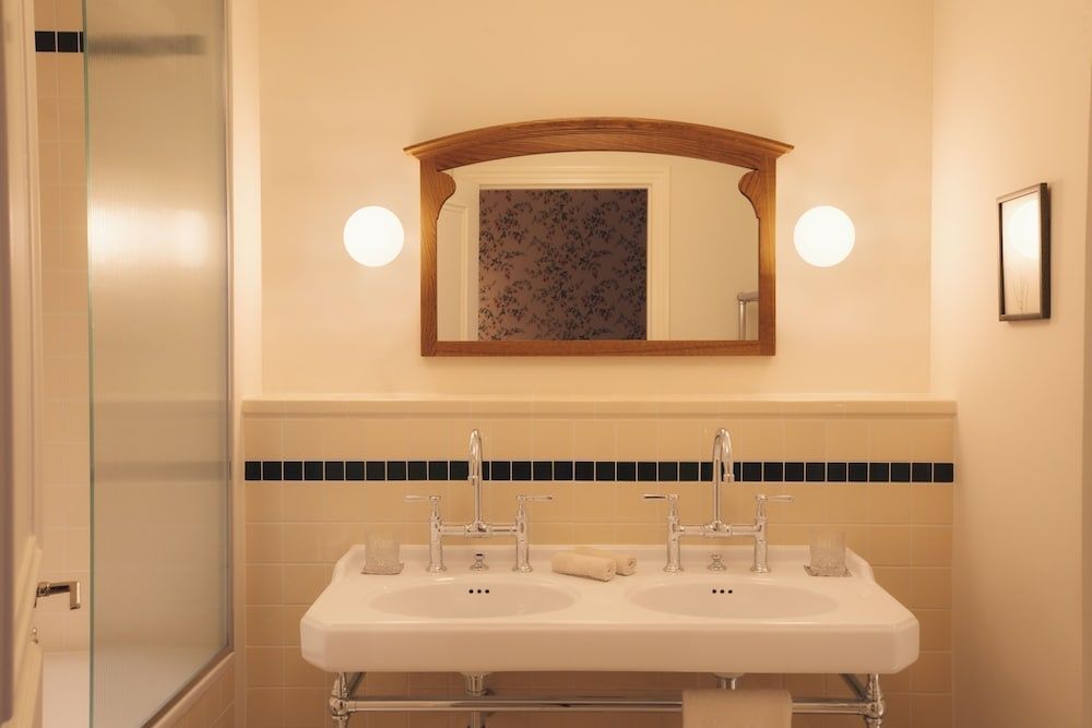 Badezimmer mit Doppelwaschbecken, Holzspiegel und wandmontierten Lampen.