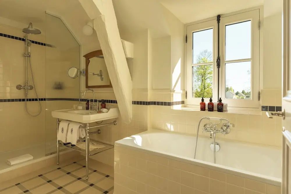 Badezimmer mit Badewanne am Fenster, freistehendem Waschtisch und Dusche.