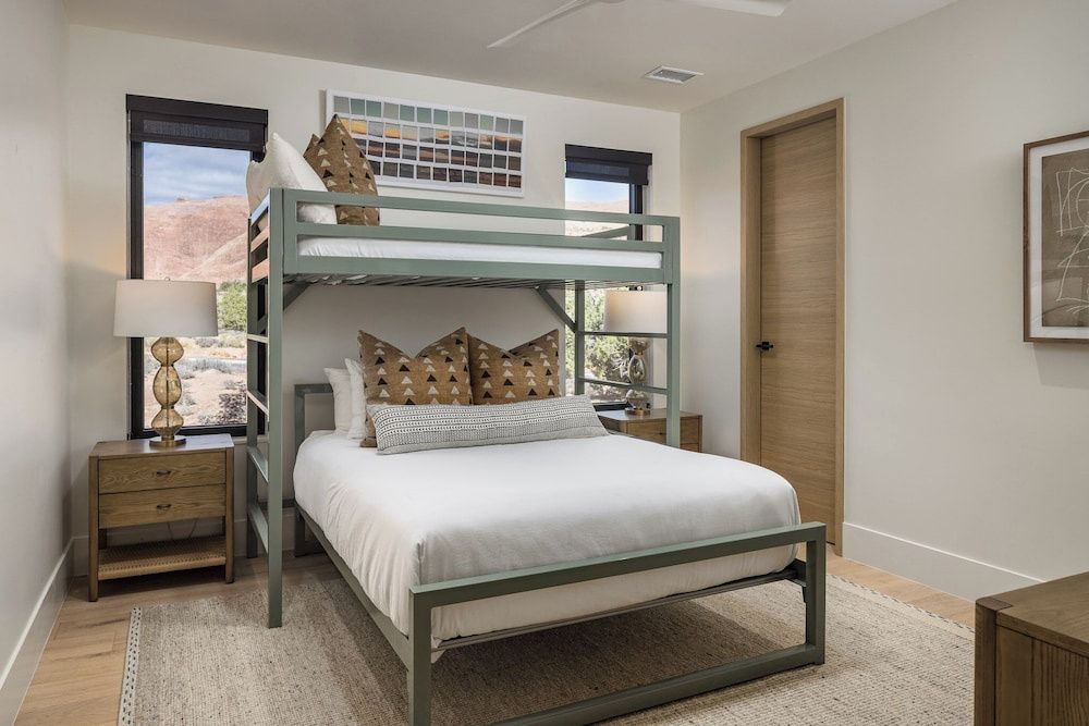 Schlafzimmer mit grünem Etagenbett und Fenstern mit Blick auf die Landschaft.