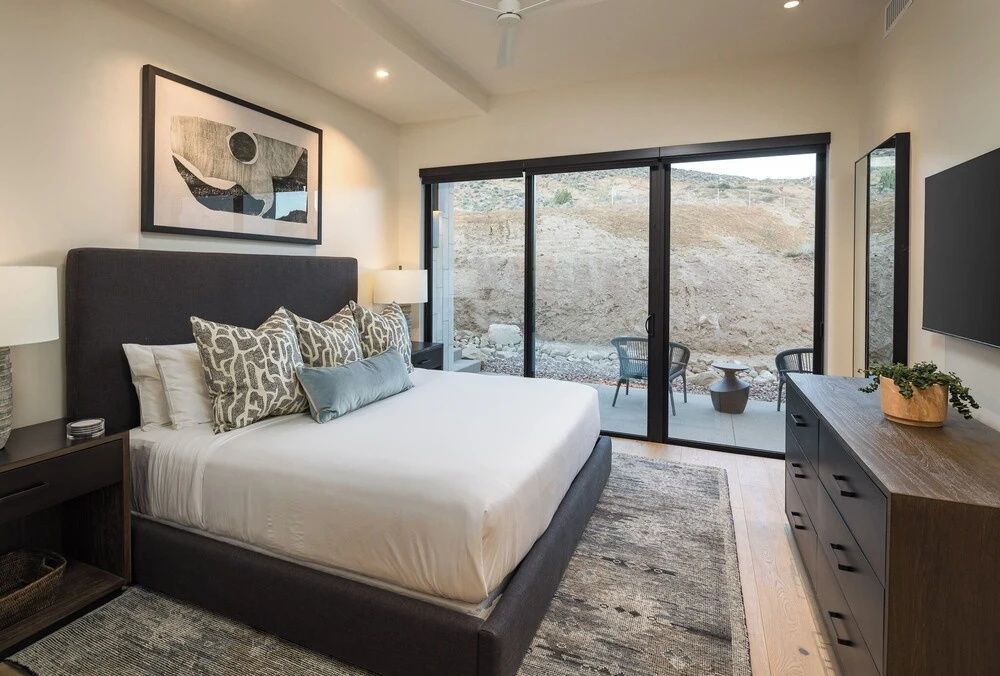 Schlafzimmer mit großem Doppelbett und Schiebetür mit Blick auf die Felslandschaft.