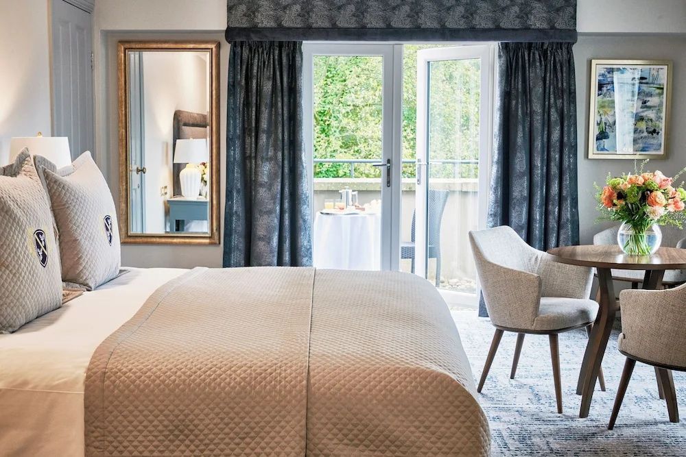 Schlafzimmer mit Doppelbett, Sessel und geöffneter Balkontür mit Blick ins Grüne.