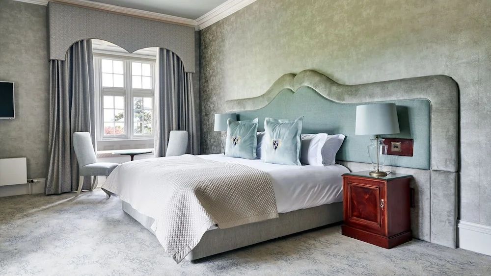 Schlafzimmer mit großem Doppelbett, hellgrünem Kopfteil und tageslichtdurchflutetem Fenster.