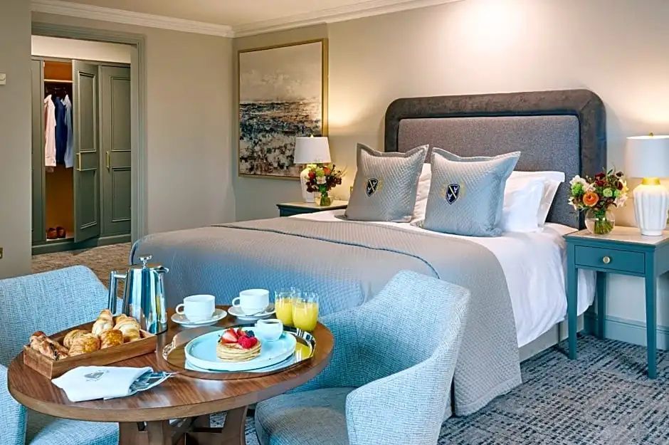Einladendes Hotelzimmer mit großem Doppelbett, gepolstertem Kopfteil und Esstisch.