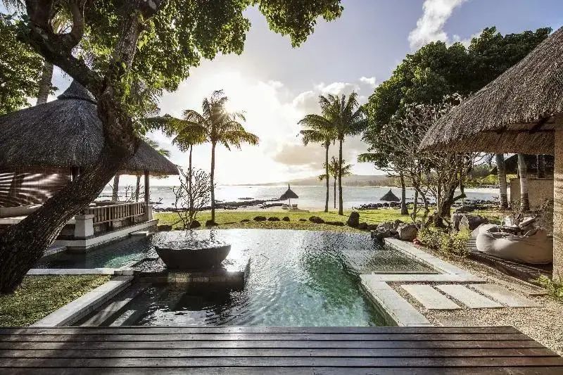 Außenpool einer Villa mit Blick auf Palmen, Strand und das Meer bei Sonnenschein.