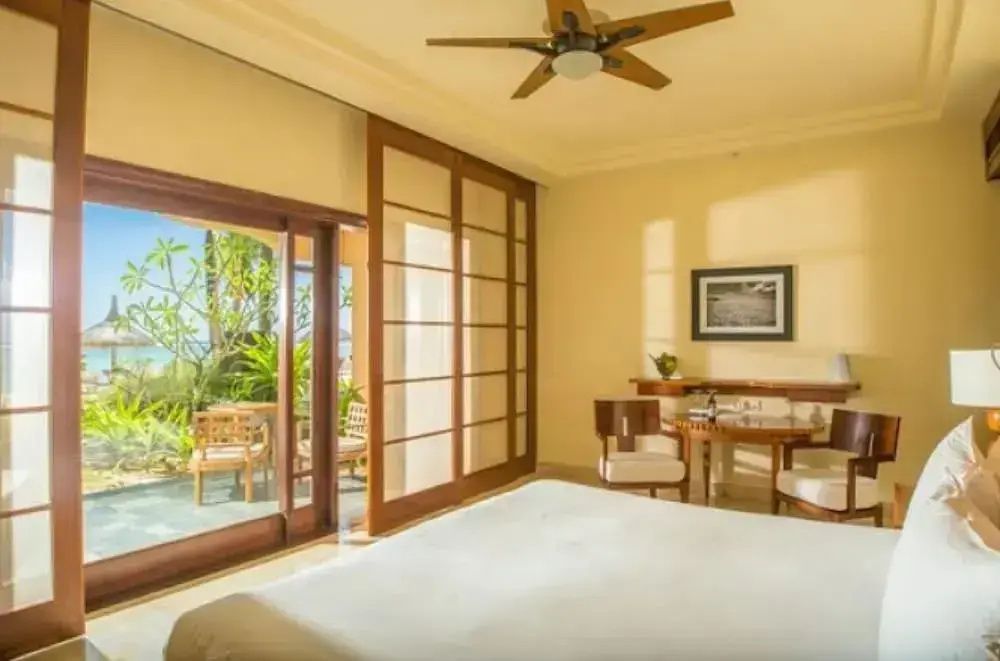Helles Schlafzimmer mit Deckenventilator und Schiebetür zur Terrasse.