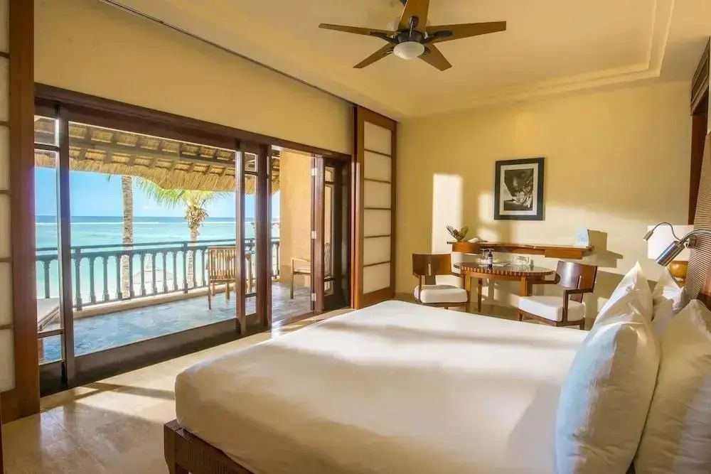 Helles Hotelzimmer mit großem Doppelbett, Holzmöbeln und Balkon mit Meeresblick.