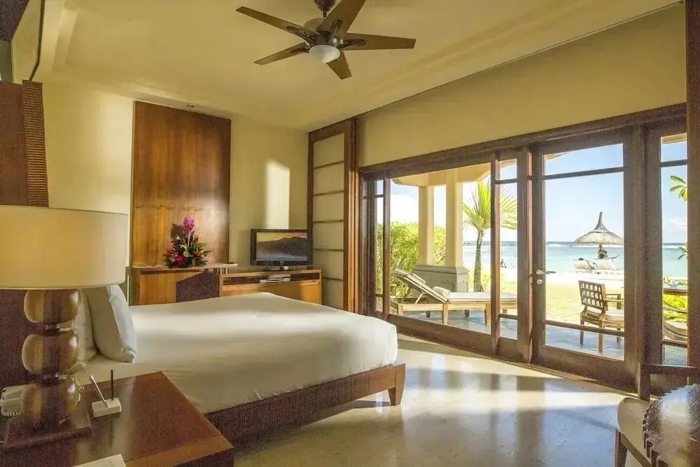 Schlafbereich mit Doppelbett, TV und Glas Schiebetür zum Strand.