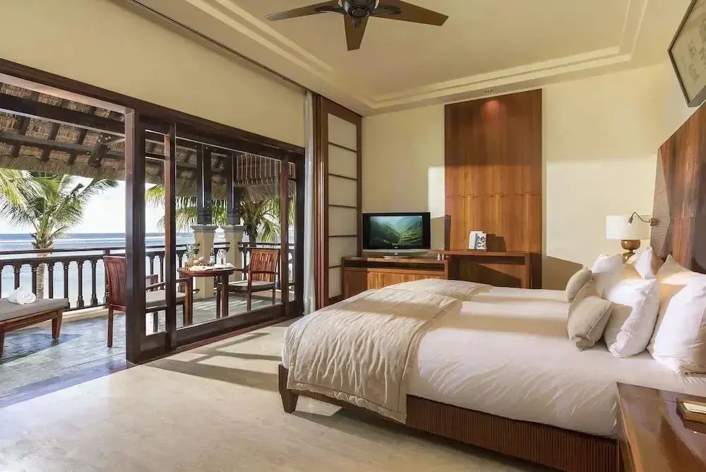 Geräumiges Hotelzimmer mit Kingsize Bett, Fernseher und Schiebetür zum Balkon mit Meerblick.