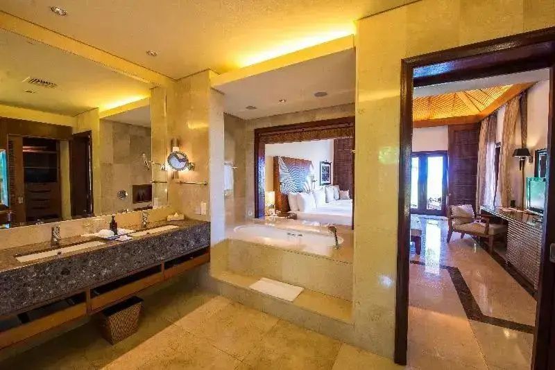 Marmorbadezimmer mit Waschtisch, großer Badewanne und Durchblick in das angrenzende Schlafzimmer.
