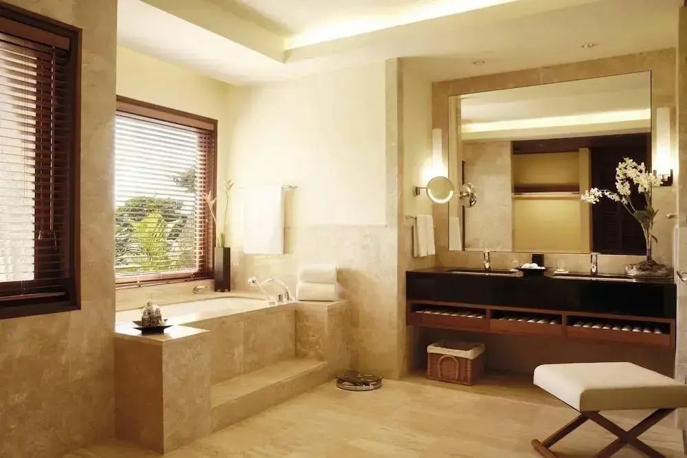 Großes Badezimmer mit eingelassener Badewanne und dunklem Waschtisch.