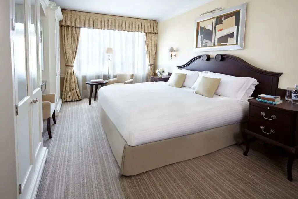 Helles Hotelzimmer mit einem großen Doppelbett, gestreiftem Teppich und einem Fenster.