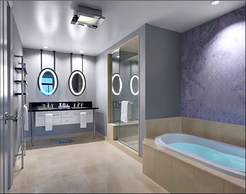Modernes Badezimmer mit einer Badewanne, Doppelwaschtisch und zwei beleuchteten Spiegeln.
