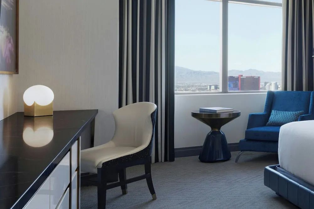 Schreibtischecke im Hotelzimmer mit weißem Stuhl und Blick aus dem Fenster.