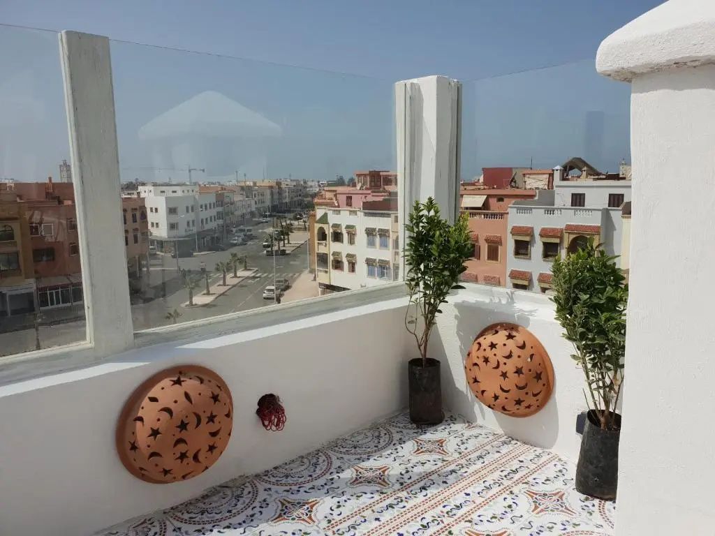 Geflieste Dachterrasse mit Glasgeländer und Blick über die Gebäude der Stadt.
