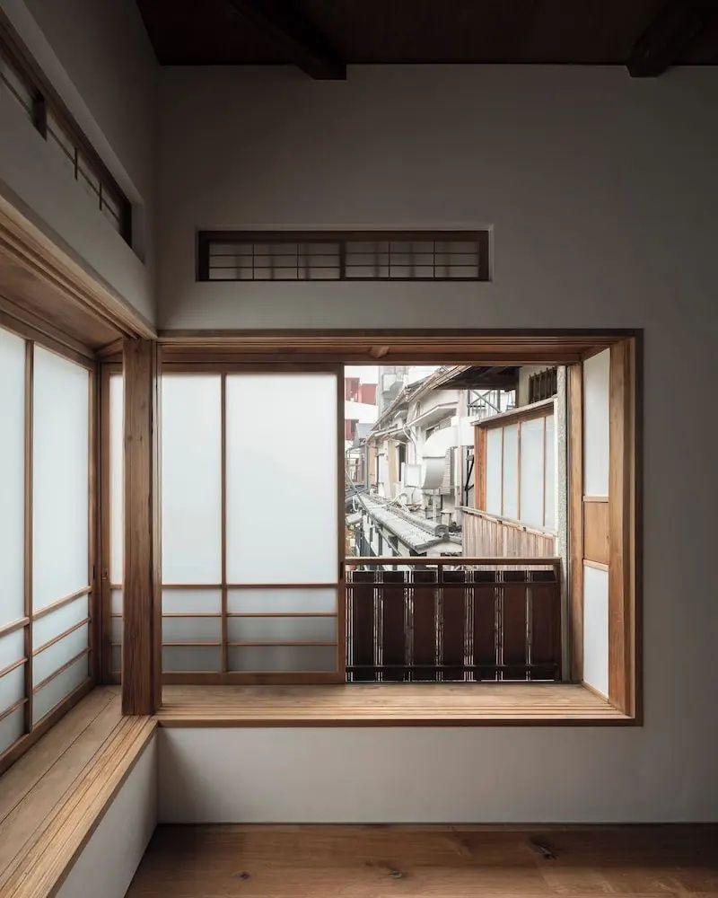 Traditionelles japanisches Holzfenster mit Schiebeelementen und Blick auf umliegende Gebäude.