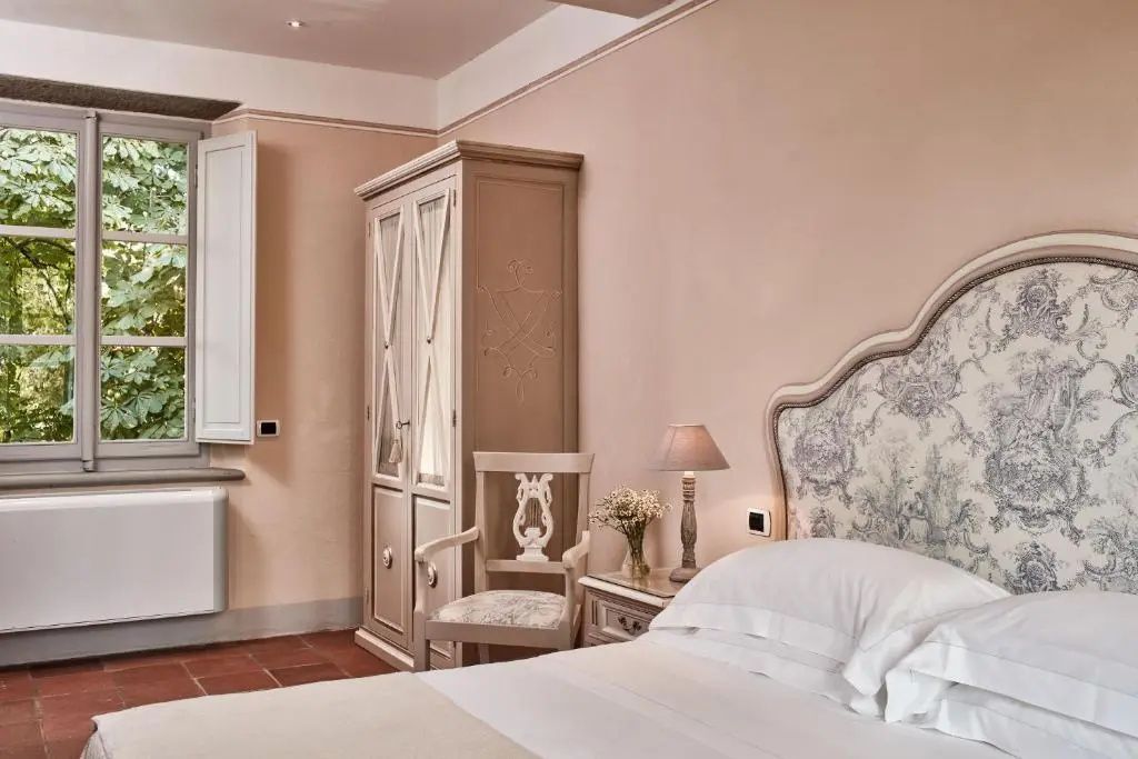 Hotelzimmer mit Doppelbett, Holzschrank und Terracotta Bodenfliesen.