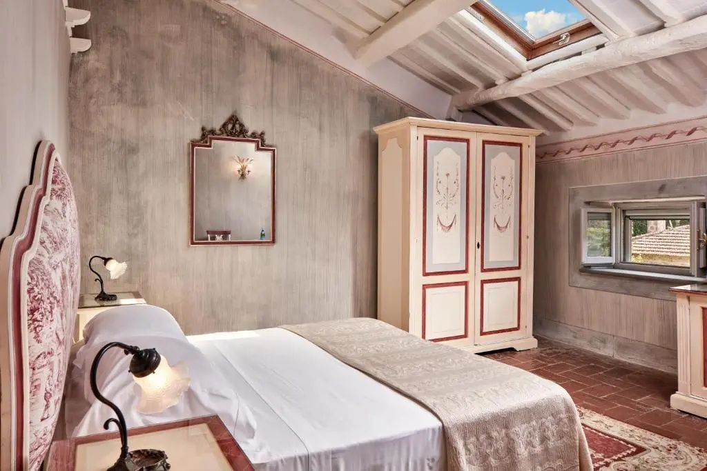 Hotelzimmer unter dem Dach mit Holzschrank, Doppelbett und Dachfenster.
