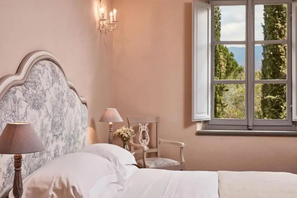 Blick durch ein geöffnetes Fenster im Schlafzimmer auf die Landschaft.