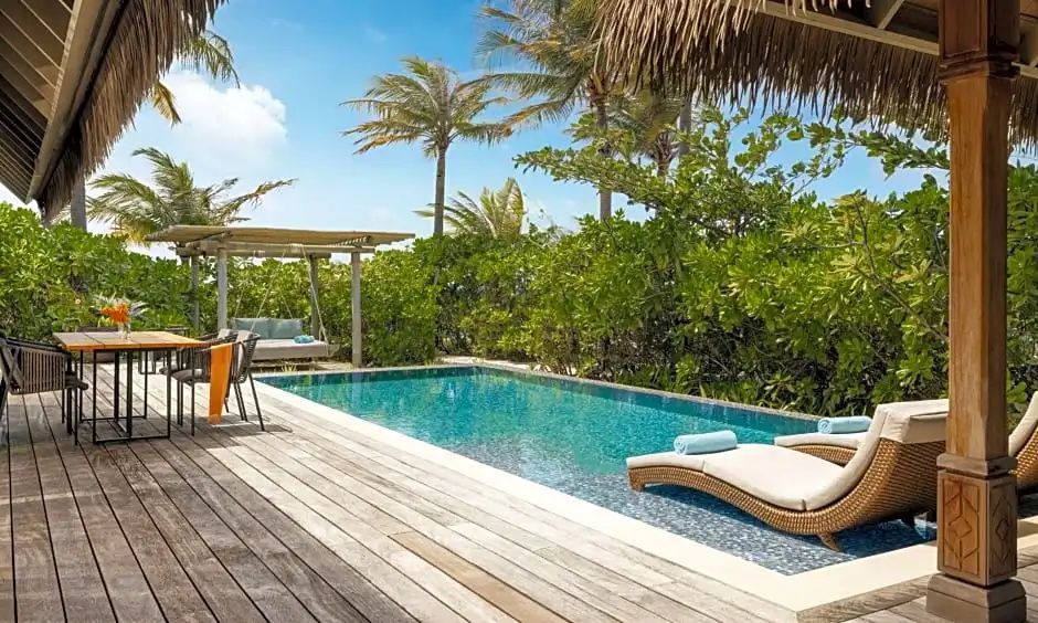 Eigener Swimmingpool auf einer Holzterrasse mit Sonnenliegen und Palmen.