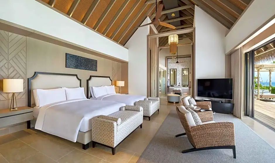 Geräumiges Schlafzimmer einer Villa mit zwei Betten, Deckenventilator und hohen Holzdecken.
