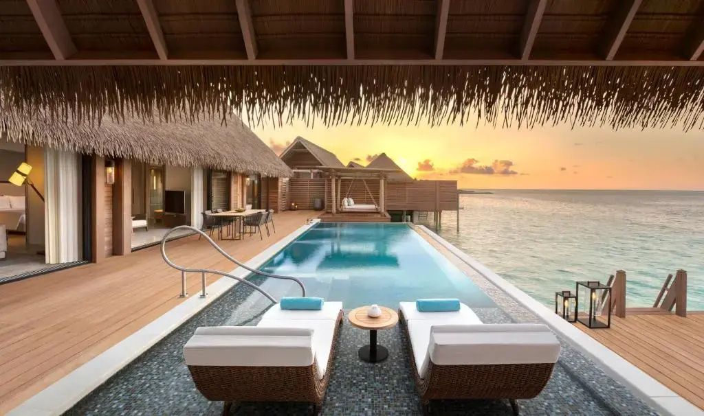 Pool auf einer Holzterrasse mit zwei Sonnenliegen bei Sonnenuntergang und Blick aufs Meer.