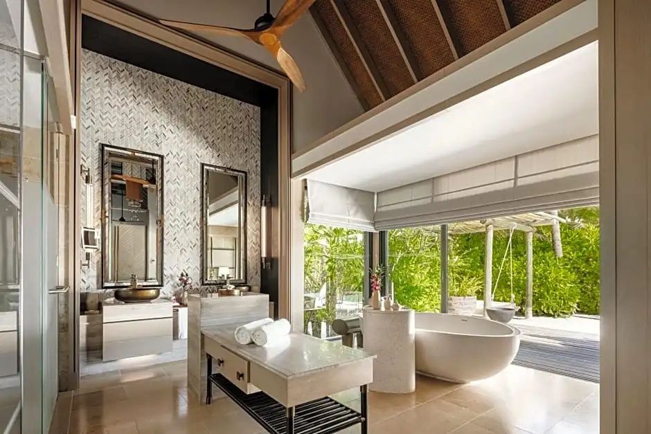Badezimmer mit frei stehender Badewanne, Doppelwaschtisch und Blick auf die Bepflanzung.