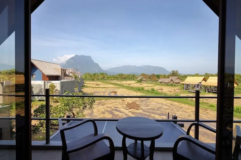 Blick vom Balkon mit zwei Stühlen und Tisch auf eine Landschaft mit Bergen.