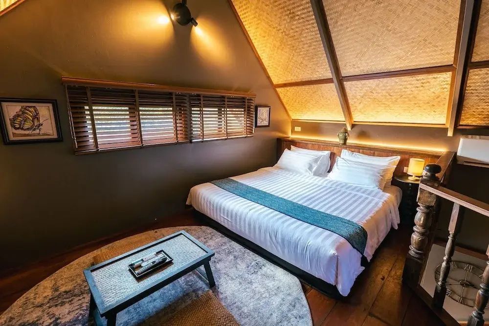 Schlafbereich unter einer Dachschräge mit Doppelbett, weißer Bettwäsche und kleinem Tisch.