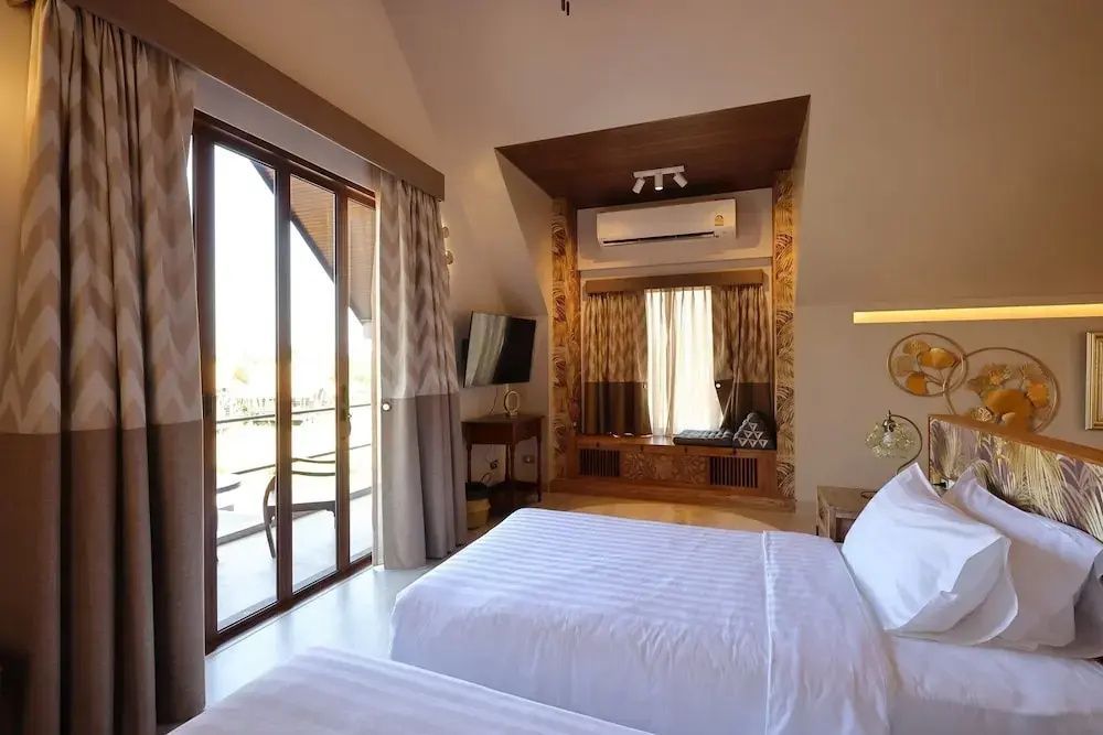 Hotelzimmer mit zwei Betten, Fernseher an der Wand und Sitzecke unter dem Fenster.