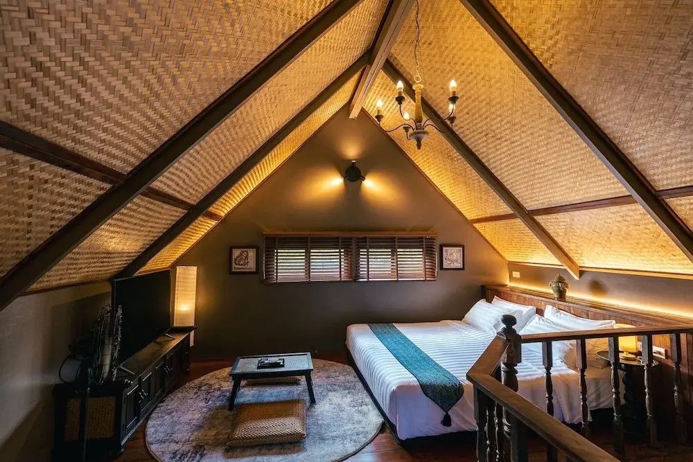 Dachgeschoss Schlafzimmer mit Doppelbett, Fernseher und gewebter Decke aus Naturmaterialien.