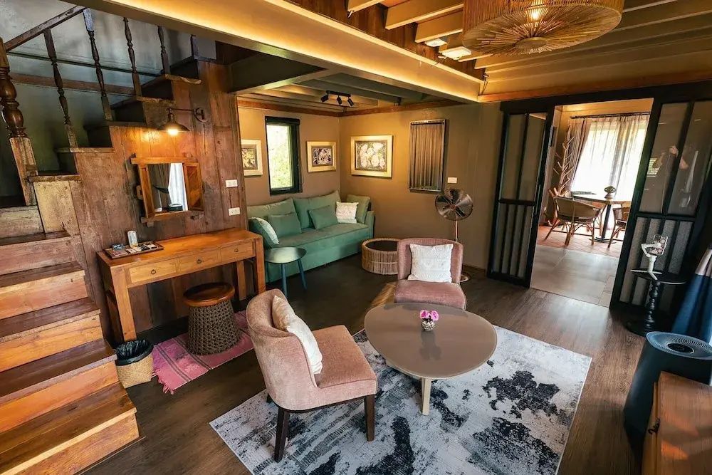 Wohnbereich eines Zimmers mit Holzverkleidung, grünem Sofa und rosa Sesseln.