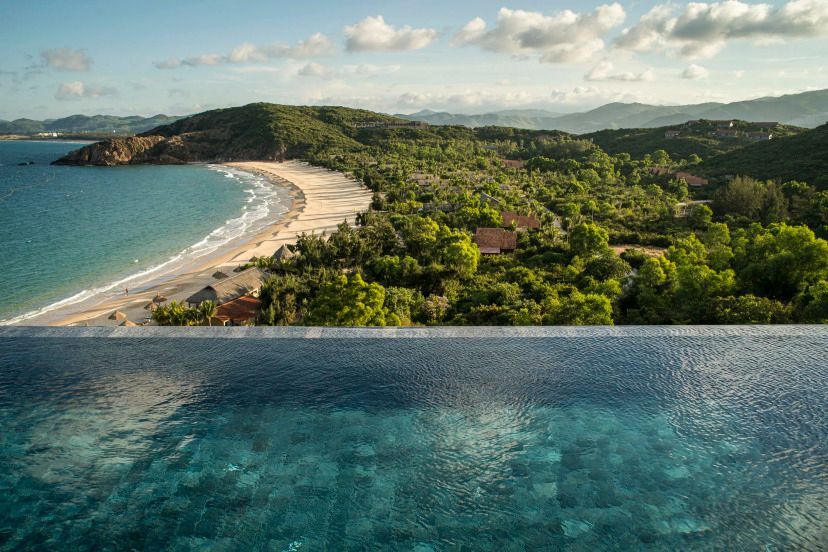 Infinity-Pool mit Blick auf unberührten Strand und grüne Landschaft