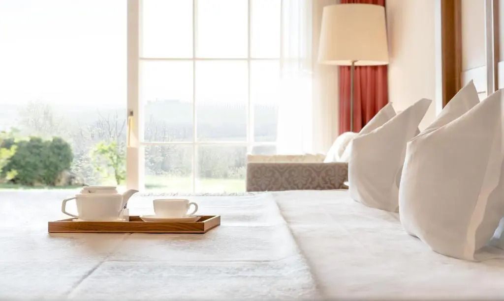 Helles Zimmer mit Panoramafenster und gemütlichem Bett mit Teeservice