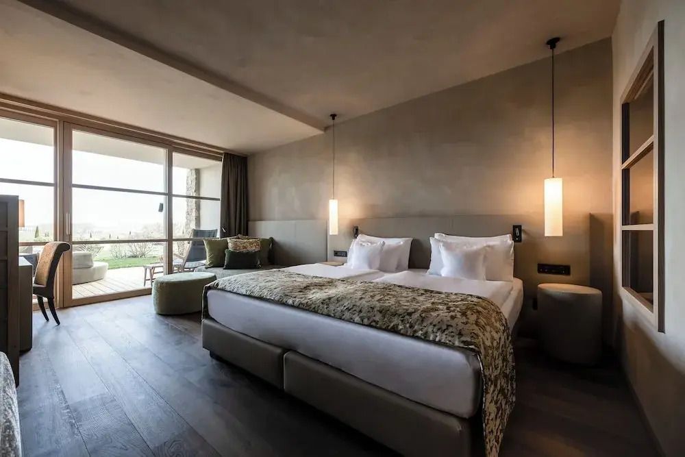 Doppelbett im stilvoll eingerichteten Zimmer mit Balkon und Ausblick